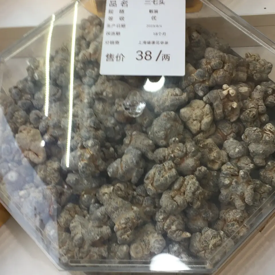 A shop bin of dried Panax notoginseng heads with a price tag per tael